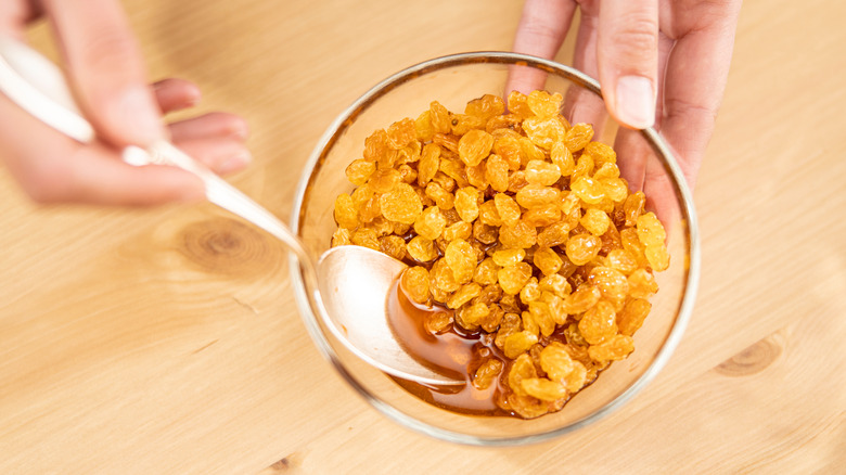 bowl of soaking golden raisins mixed by hand