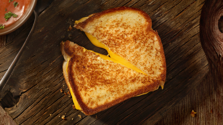 Grilled cheese sandwich sliced diagonally on wooden table