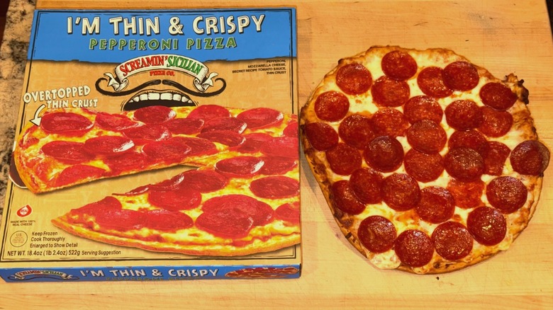 A cooked Screamin' Sicilian I'm Thin & Crispy Pepperoni Pizza sits next to its product box
