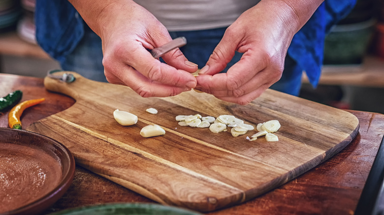 hands over sliced garlic on cutting board