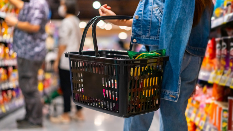 Someone holding a basket in a grocery store while shopping