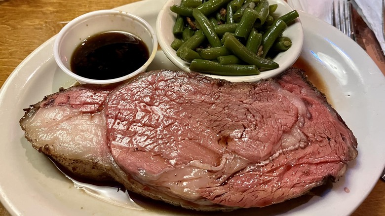 Texas Roadhouse's prime rib on a plate, next to a side of green beans.