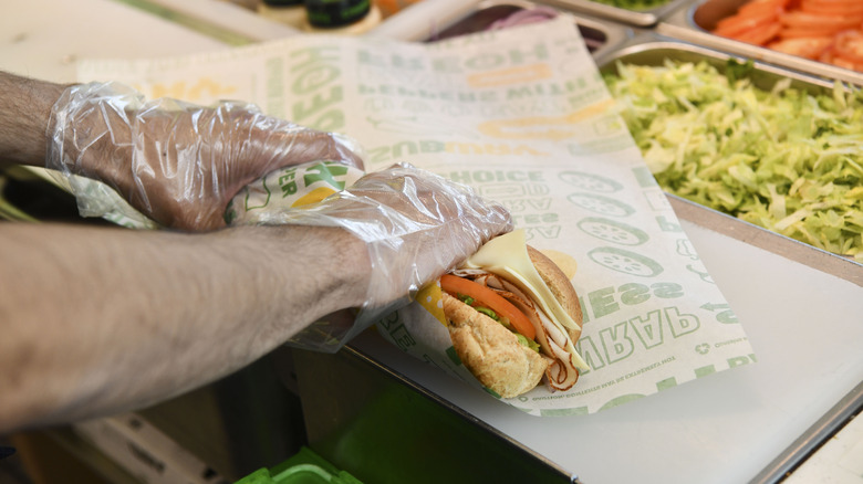 A sandwich artist wrapping up a sub