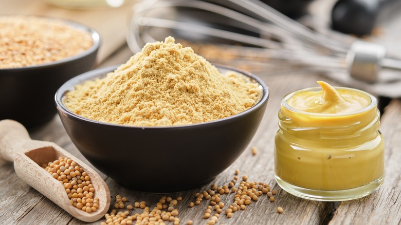 mustard powder, seeds, and paste displayed on wooden counter