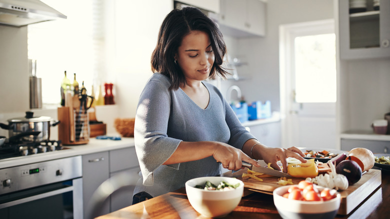 Woman in kitchen cutting vegetables
