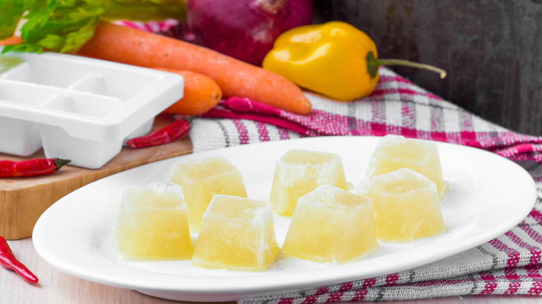 Ice cubes of broth on plate with vegetables