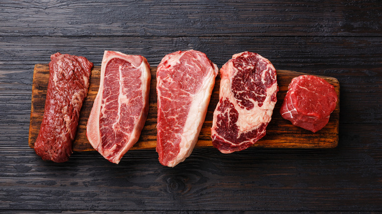 Different cuts of raw steak with varying marbling