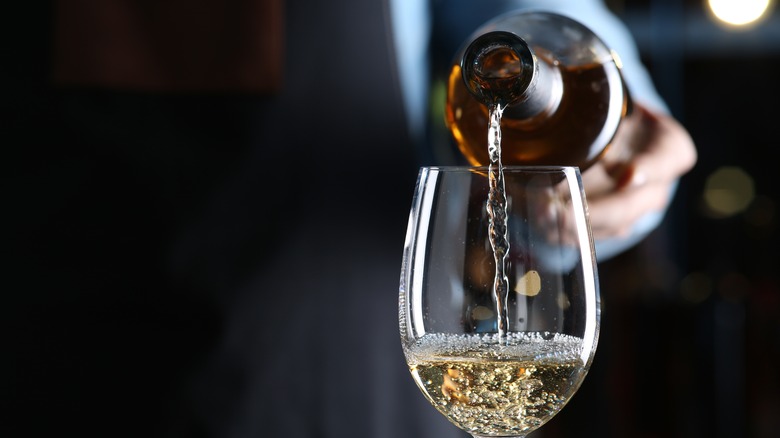 Bartender pouring white wine while holding punt