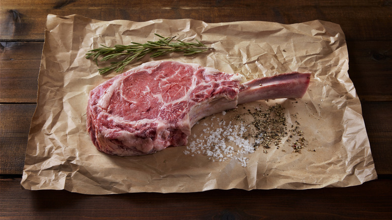 steak on butcher paper with rosemary, salt, and pepper
