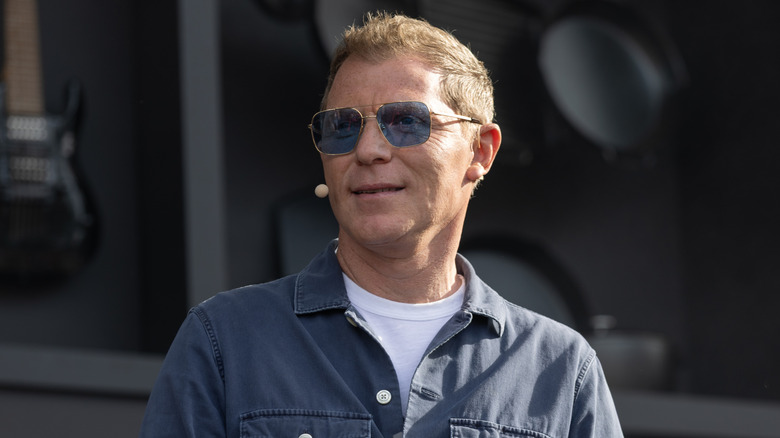 Bobby Flay speaking on stage with sunglasses on