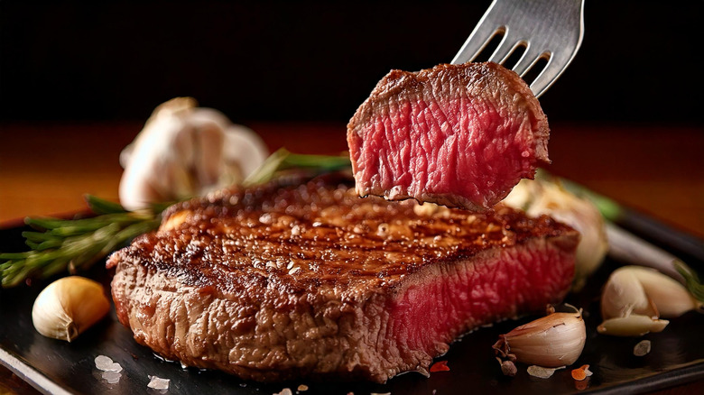 Cut steak surrounded by garlic and herbs