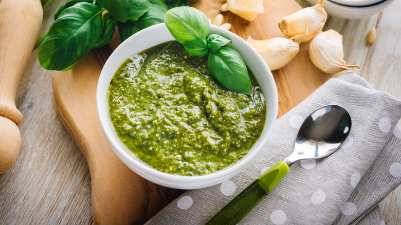 White bowl of green pesto with basil