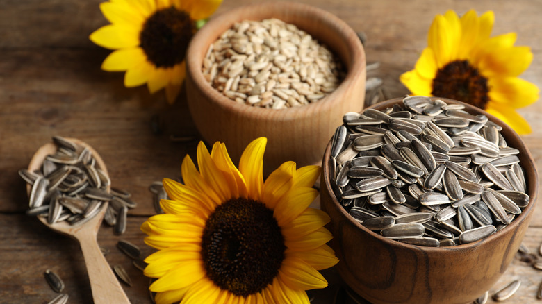 Wooden bowls of sunflower seeds with sunflowers