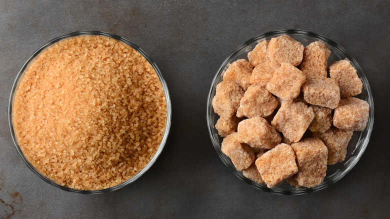 Turbinado raw sugar and brown sugar cubes in glass bowls