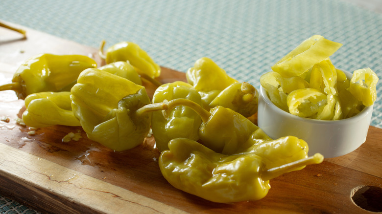Tray of whole pepperoncini with sliced peppers in a ramekin