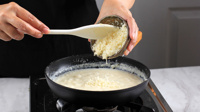 Adding shredded cheese to bechamel sauce to make mornay sauce