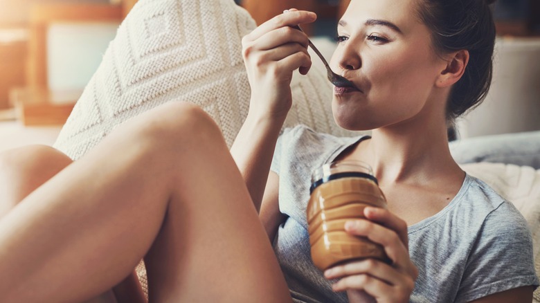 woman eating peanut butter from a jar