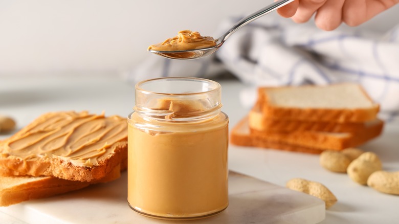 a person scooping peanut butter out of a jar with a spoon