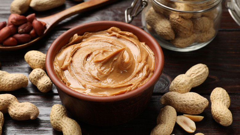 A table spread of shelled peanuts, raw peanuts, and peanut butter