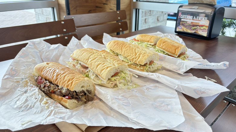 four sub sandwiches on a wooden board