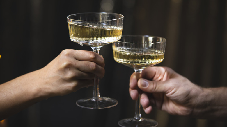 two hands clinking champagne glasses