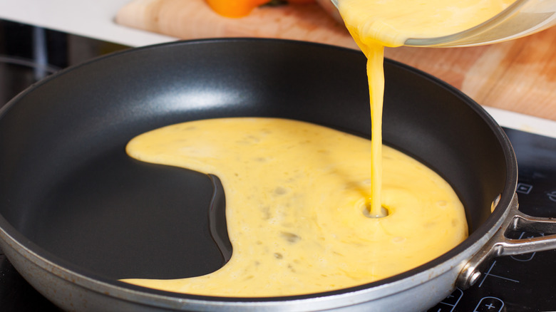 pouring whisked eggs into pan