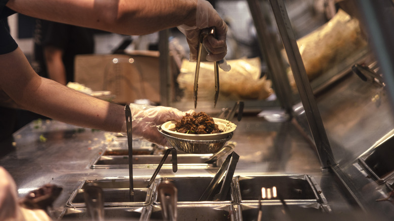 Chipotle working scooping carnitas