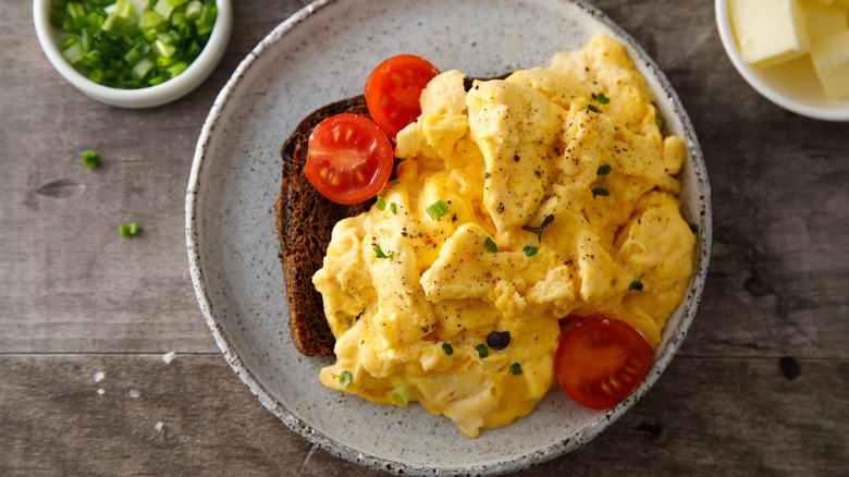 Plate of scrambled eggs and tomatoes on toast