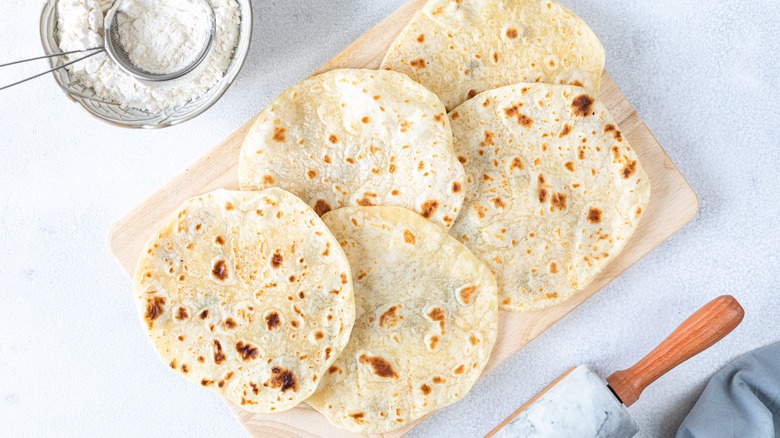 bird's eye view of flour tortillas besides bowl of flour