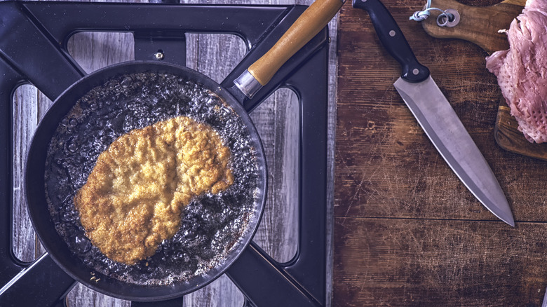 Schnitzel frying in pan full of oil