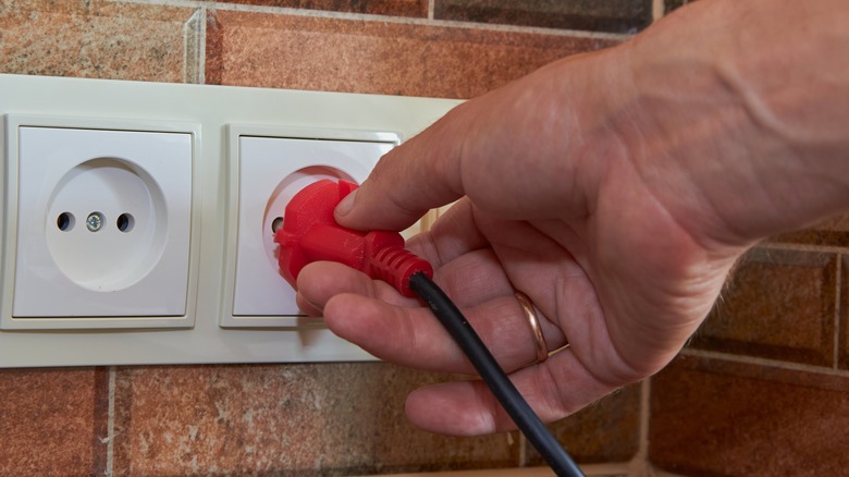 Hand pulling out a plug from an outlet
