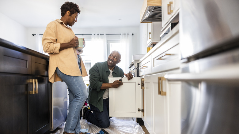 People installing off-white cabinets in a kitchen