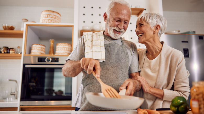 An older couple cooking together in a kitchen.