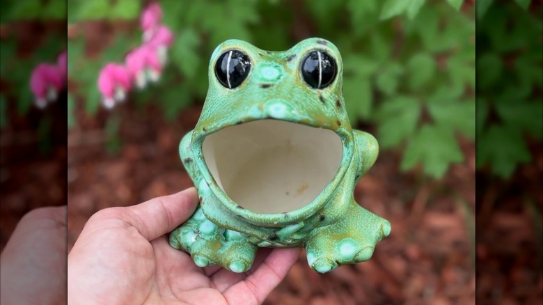 Someone holds a vintage ceramic frog.