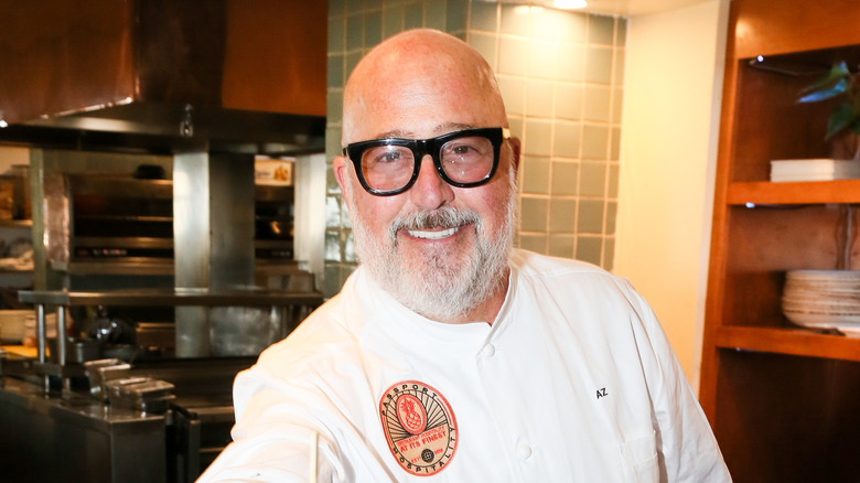 Andrew Zimmern smiling in a kitchen