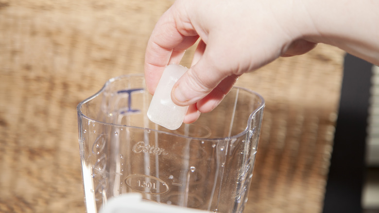 Dropping ice cube into blender