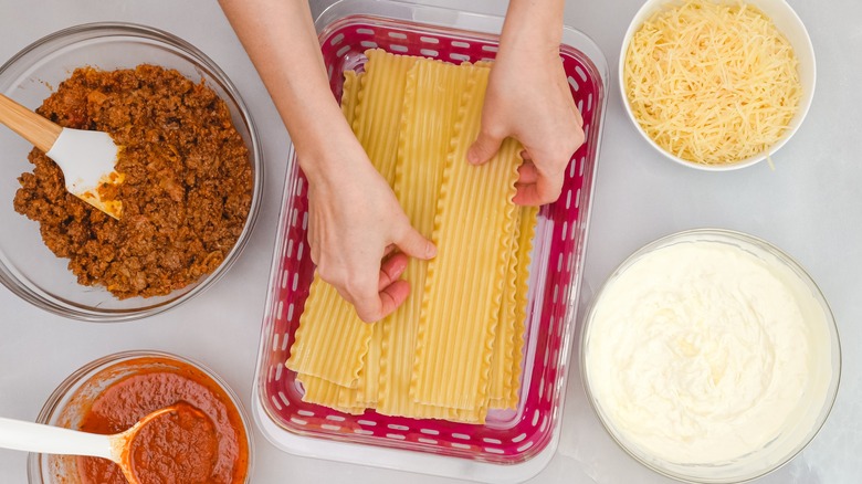 person assembling a lasagna