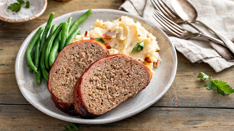 Plate of dry-looking meatloaf with green beans and mashed potatoes