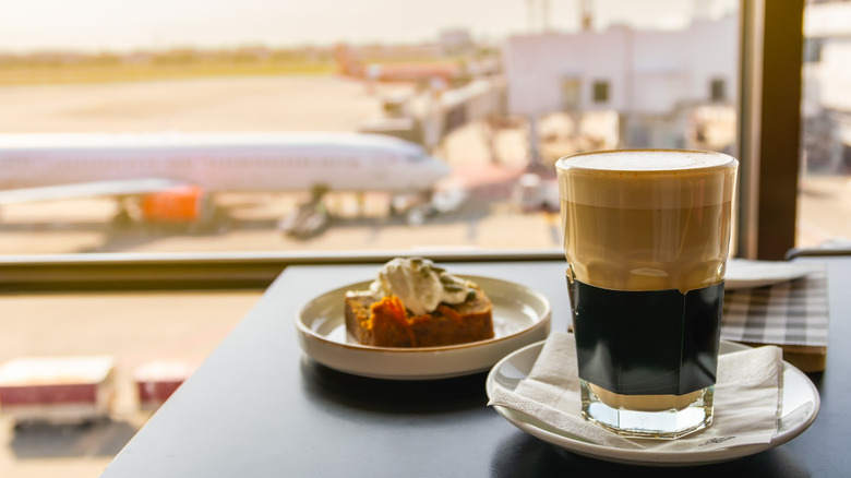 A latte and a pastry at a table overlooking an airport runway