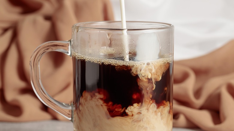 Creamer being pouring into a mug of coffee