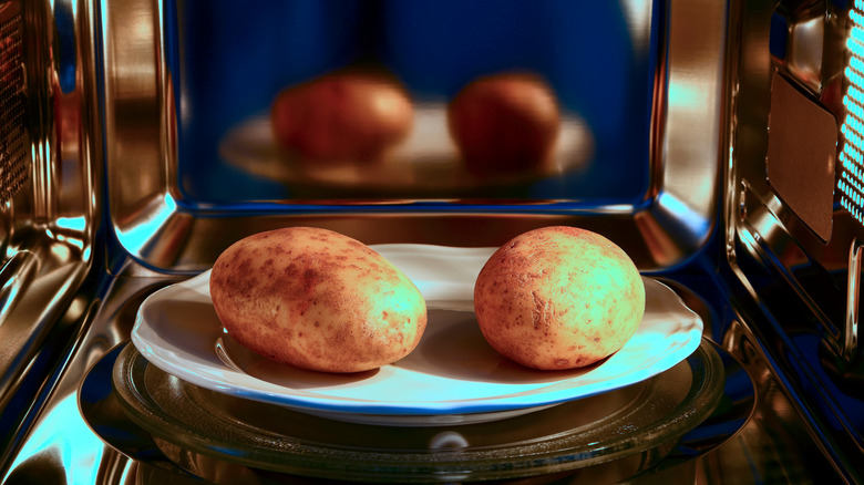 two potatoes on a plate in the microwave