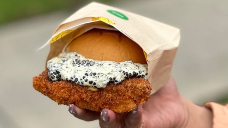 A hand holding a caviar-topped fish sandwich from Daybird.