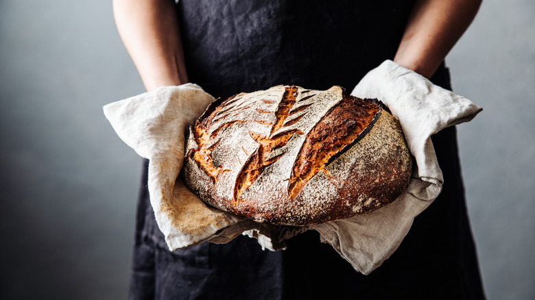 Person holding a loaf of sourdough bread
