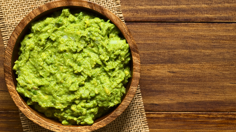 Smashed avocado in wooden bowl
