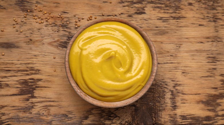Yellow mustard in wooden bowl