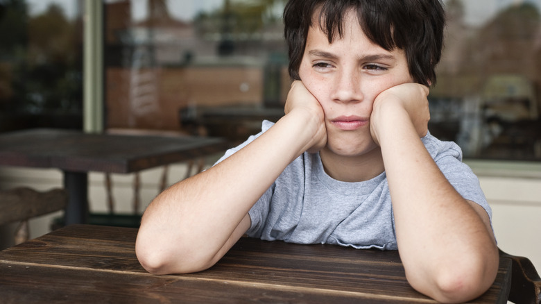 A child leaning both elbows on cafe table