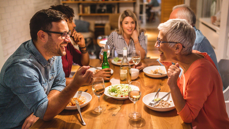 Dinner party guests eating with elbows on table