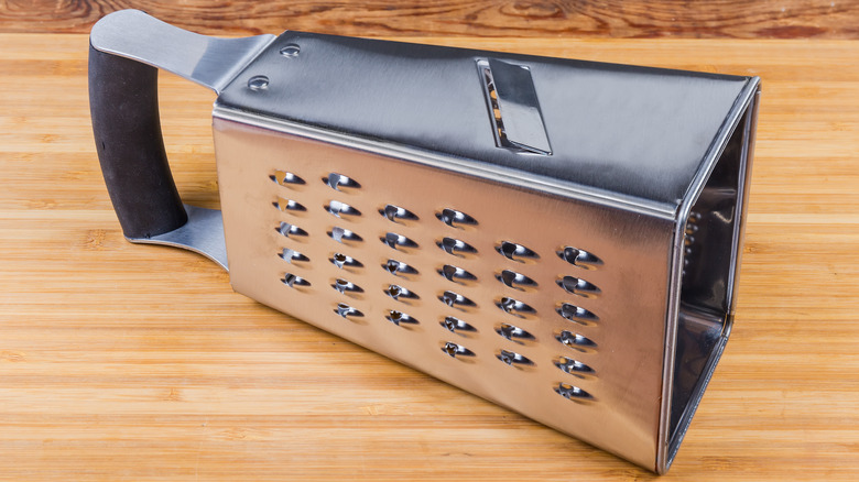 Sideways metal cheese grater on wood counter