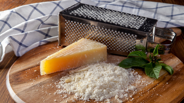 Box grater on cutting board with grated Parmesan cheese