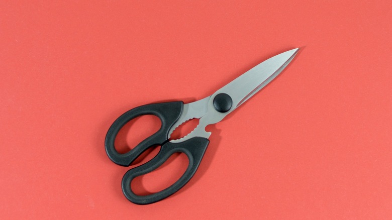 pair of kitchen scissors on red background